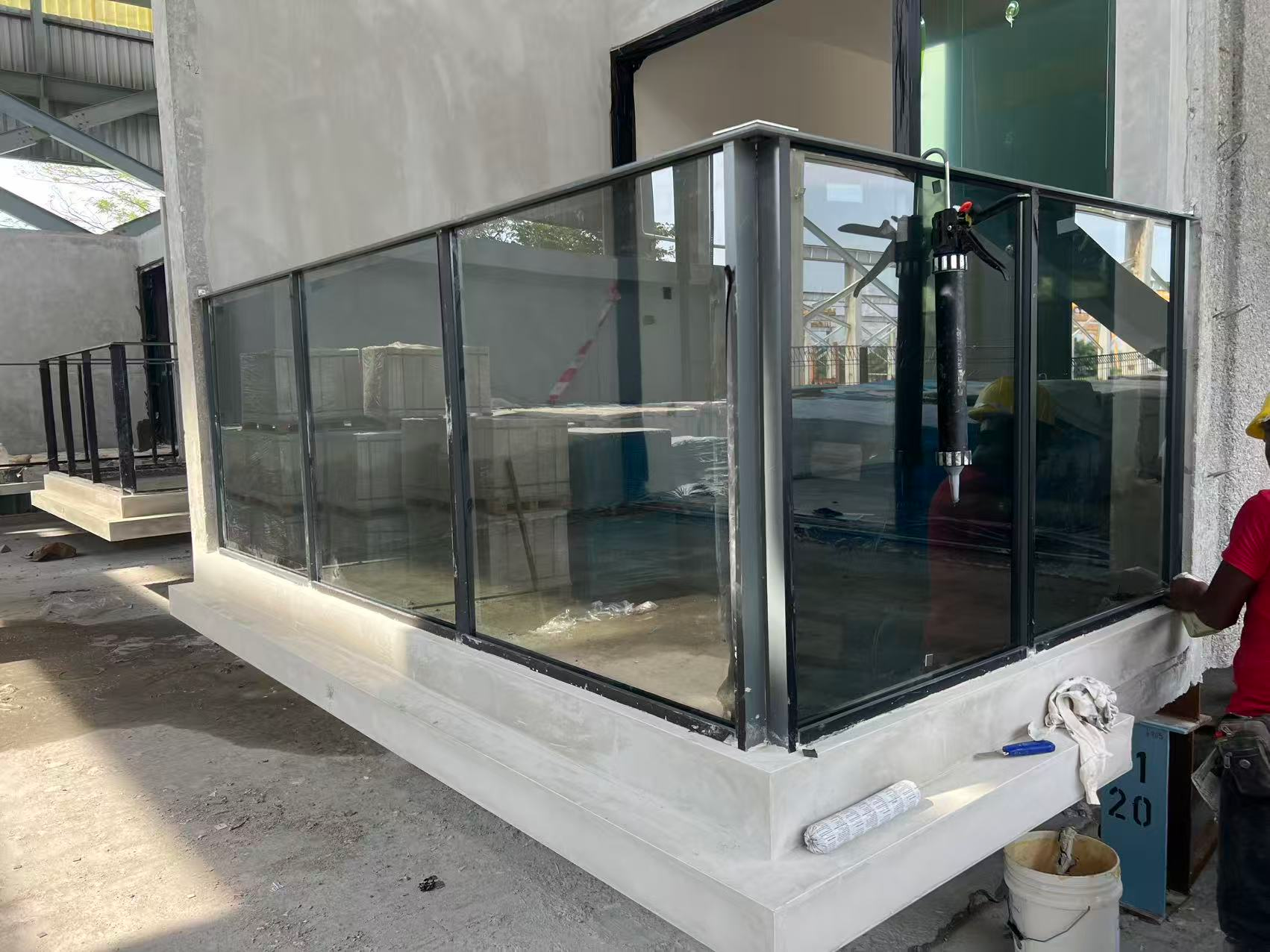 Grey laminated glass installed in a corner balcony railing at PARKTOWN Residence during construction.